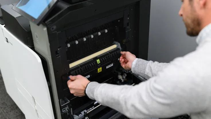 Technicien réalisant le dépannage d'un photocopieur professionnel en entreprise